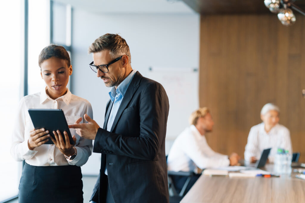 Multiracial woman and man using tablet computer in office