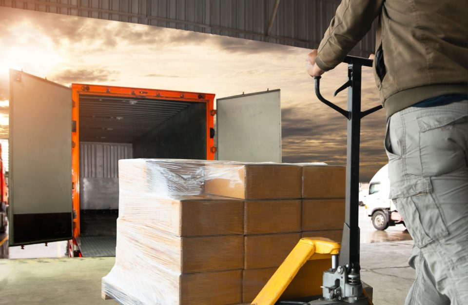 A warehouse worker takes a pallet of goods to a loading bay to be loaded onto a lorry.