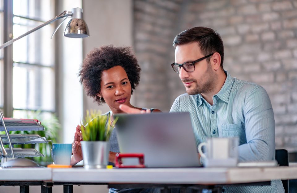 Photo of two coworkers working together on new project in office.