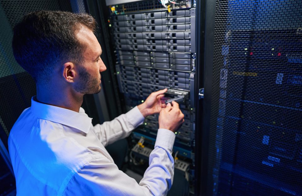 Caucasian network engineer in white shirt is finding and troubleshooting server in tech place