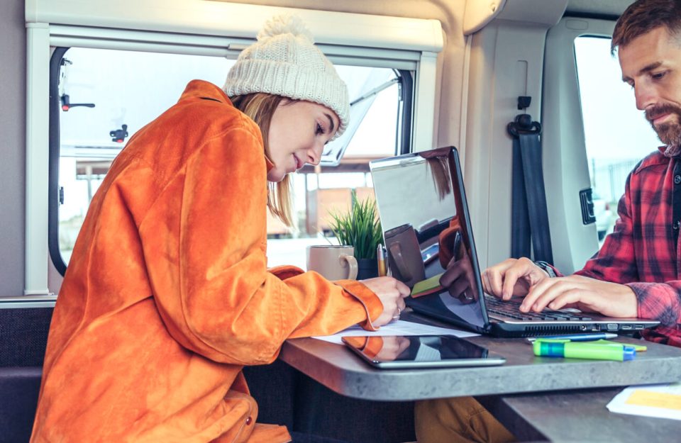 Young woman and man telecommuting during a camper van trip